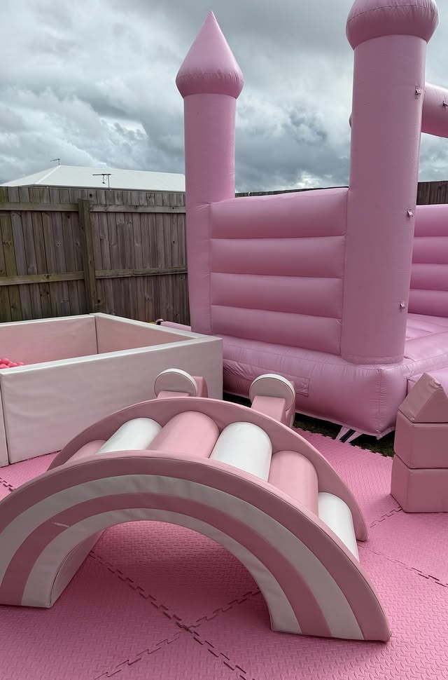Pink soft play rainbow, ball pit and bounce house at a first birthday